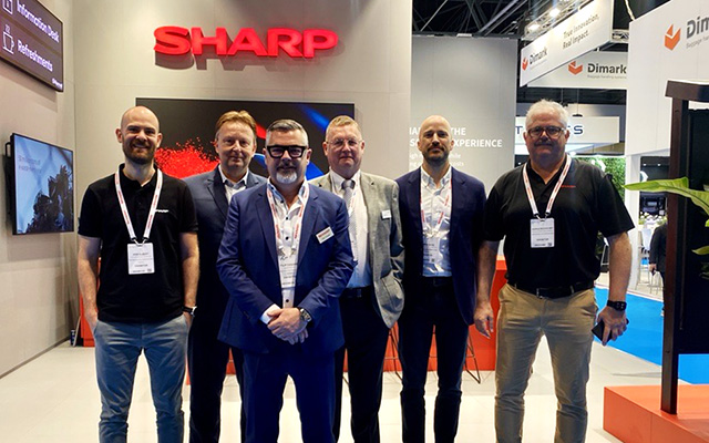 Six gentlemen standing at a trade show exhibition
