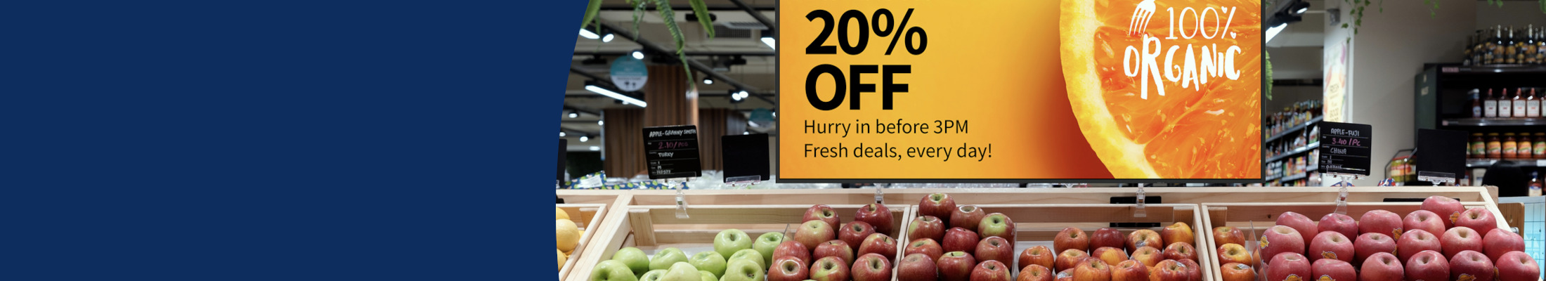 Red and green apples displayed in a supermarket with a promotional sign above